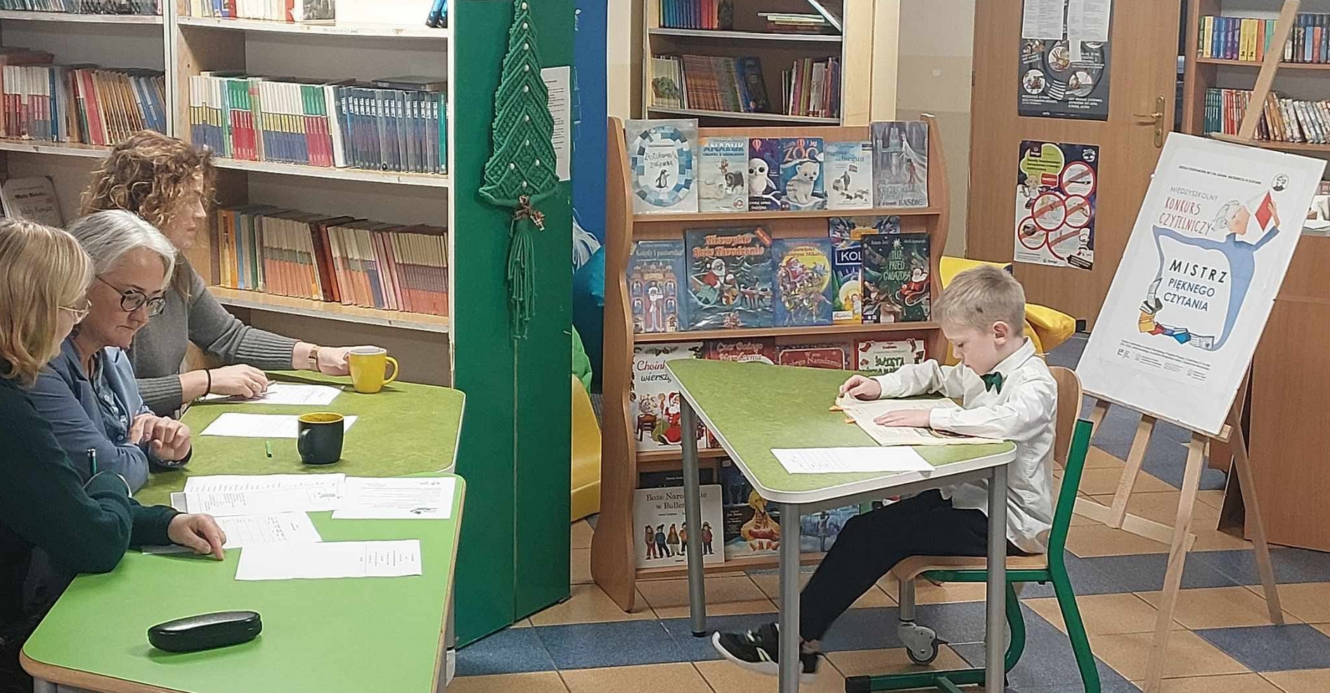 Uczeń siedzi i czyta książkę w bibliotece. W tle napis mistrz pięknego czytania