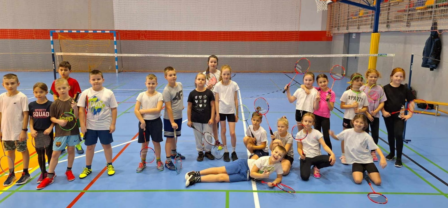 Uczniowie stoją na hali sportowej. Turniej badmintona