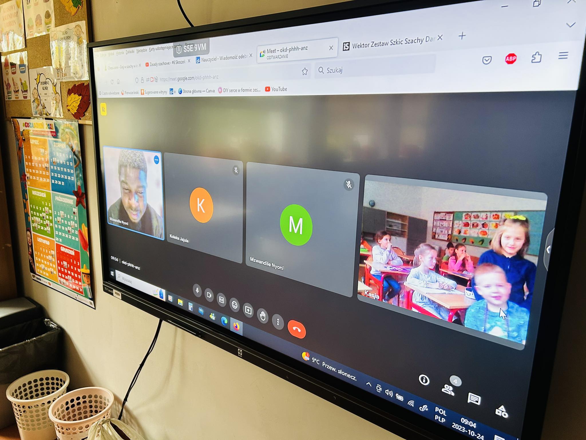 Na tablicy interaktywnej zajęcia online z nativ speaker w okienku pierwszym, w drugim dzieci siedzą i patrzą w kamerkę.